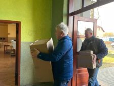 Burmistrz gminy Weimar/Lahn niosący karton z darami za nim idzie Komendarnt Marcin Czarciński, który również niesie karton z darami.